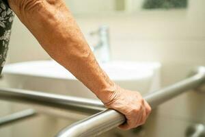 Asian elderly woman patient use toilet bathroom handle security in nursing hospital, healthy strong medical concept. photo