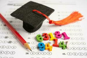 Graduation gap hat and pencil on answer sheet paper, Education study testing learning teach concept. photo