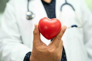 médico sosteniendo un corazón rojo en la sala del hospital, concepto médico fuerte y saludable. foto