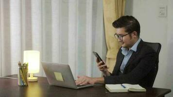 Asian businessman working on using phone and laptop computer at home office,working at home on the Internet. video