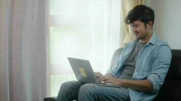 asiático hombre sonriente trabajando en línea con ordenador portátil a hogar oficina, teletrabajo concepto. video