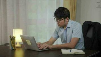 asiático hombre con cuello dolor o oficina síndrome a reservando un ordenador portátil a tu escritorio a hogar. video