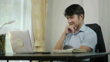 contento asiático hombre trabajando en línea con ordenador portátil a hogar oficina, teletrabajo concepto. video