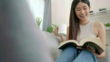 Asian young woman reading book on sofa at home. video