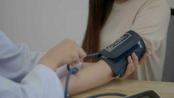 A female Asian doctor measures asian women  blood pressure during a medical consultation in  clinic office. video