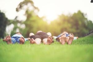 Group of children lying down on green grass outdoors in the park photo