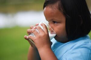 Little girl drinking milk in the park photo