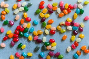 Big pile of colorful jellybeans spread out on rustic grey background photo