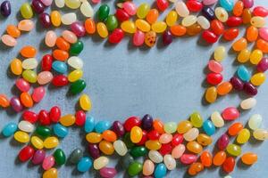 Frame of colorful jellybeans on rustic grey background with copy space photo