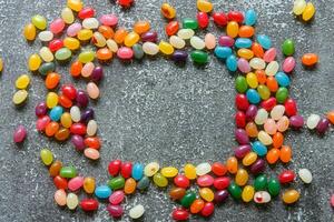 Frame of colorful jellybeans on rustic grey background with copy space photo