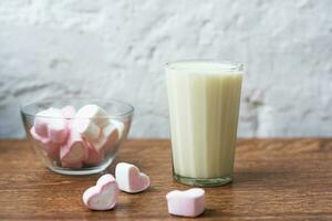 transparent plate with heart-shaped marshmallows and a glass of fresh milk on the table. breakfast. gentle combination photo