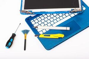 Wizard repairs laptop with tools and hands on the blue wooding table. top view photo