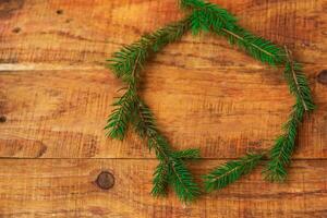 A round frame of Christmas tree branches on a wooden background. New Year's, Christmas background. photo