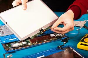 Wizard repairs laptop with tools and hands on the blue wooding table. top view photo