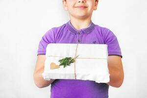 Portrait of a lovely cute boy in very peri t-shirt holding present box in fabric packaging. zero waste concept. close-up photo