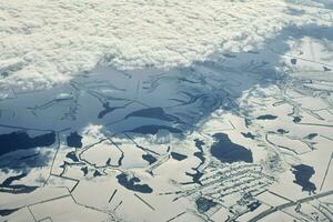 vista aérea del paisaje nublado sobre las nubes hasta ríos, carreteras, ciudades y campos cubiertos de nieve, aire invernal foto