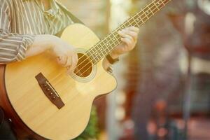 Man playing acoustic bass guitar at outdoor event, close up view to guitar neck photo