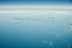 Aerial view from airplane window over clouds top to cold north sea, winter fresh frosty air photo