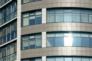 Close up view to office skyscraper windows, high business building windows with sunlight glare photo