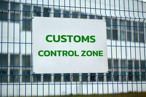 Customs control zone sign on metal fence, border symbol photo