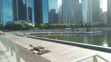 a wooden deck and body of water near tall buildings in financial district singapore video