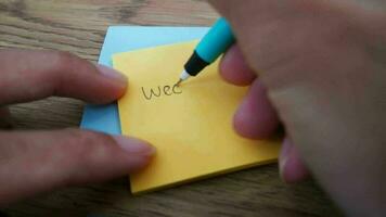 Close up of man is writing Weekend notes on yellow paper notes with blue pen and soft focus scene. video