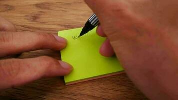 Man writing Will Be Back Soon note on a yellow paper note with black pen and soft focus scene. video