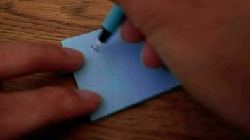 Man writing Thank You note on blue paper note with blue pen and soft focus scene. video