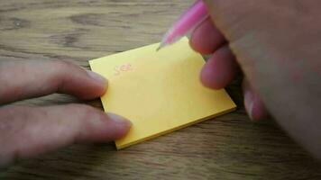 hombre escritura ver usted mañana Nota en amarillo papel Nota con rosado bolígrafo y suave atención escena. video