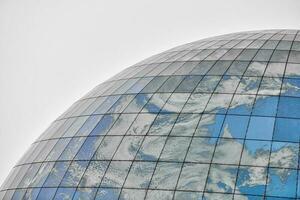 edificio moderno esférico de vidrio con reflejo de cielo azul foto