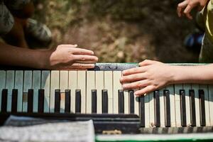 dos pequeño Niños manos jugando en piano teclado encima ver cerca arriba, niños mimos música pasatiempo foto