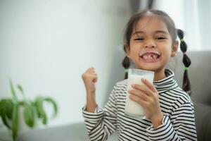 Asian little cute kid holding a cup of milk in the house. feel happy and enjoy drinking milk. photo