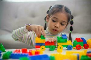 Adorable little girl playing toy blocks in a bright room photo