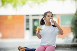 Cute schoolgirl eating outdoors the school. Healthy school breakfast for children. Food for lunch. photo