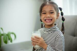 Asian little cute kid holding a cup of milk in the house. feel happy and enjoy drinking milk. photo