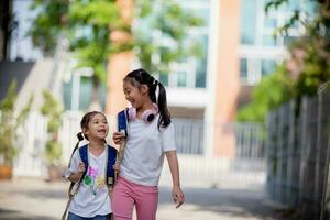 espalda a escuela. linda asiático niño niña con un mochila corriendo y yendo a colegio con divertido foto