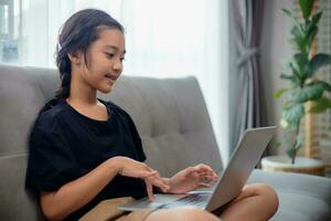 Happy girl learning the English language online with a laptop at home. photo