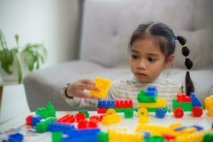 Adorable little girl playing toy blocks in a bright room photo