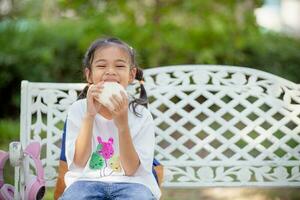 linda Chica de escuela comiendo al aire libre el escuela. sano colegio desayuno para niños. comida para almuerzo. foto