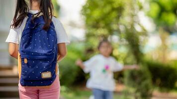 espalda a escuela. linda asiático niño niña con un mochila corriendo y yendo a colegio con divertido foto