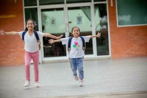 espalda a escuela. linda asiático niño niña con un mochila corriendo y yendo a colegio con divertido foto