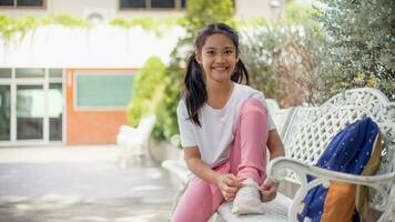 Cute little girl learning to tie shoelaces outdoors at school. photo