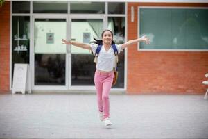 espalda a escuela. linda asiático niño niña con un mochila corriendo y yendo a colegio con divertido foto