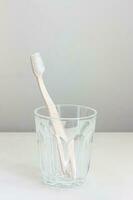 Pink toothbrush in a glass placed on a white background photo