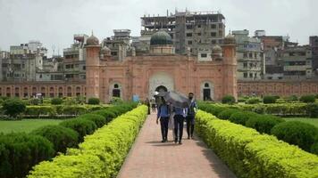 people walk through a park with a lalbagh fort mosque in the background video