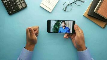 man's hands holding a smartphone with a video call on the screen