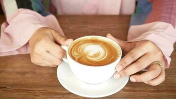 a woman holding a cup of coffee on a wooden table video