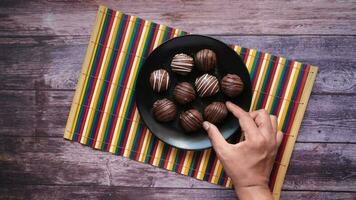 a person's hand holding a plate of chocolate covered eclaire video