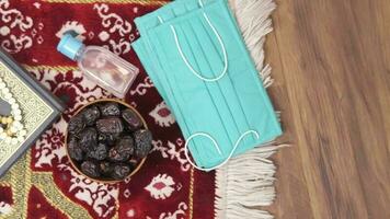 the islamic holy book with a bowl of dates, hand sanitizer and face mask. video