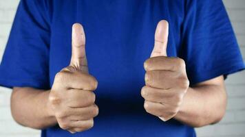a man in a blue shirt is showing two thumbs up video
